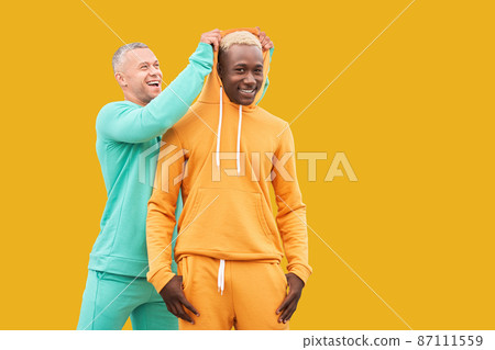 Multi ethnic friends. Two men different color black African-American ethnicity and white Caucasian ethnicity standing isolated yellow background Multi ethnic friends. Two men different color black African-American ethnicity and white Caucasian ethnicity standing isolated yellow background 87111559