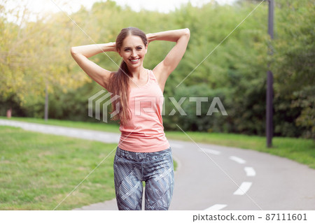 Woman runner stretching arms before running summer park 87111601