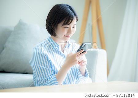 A woman watching a smartphone A woman watching a smartphone 87112814