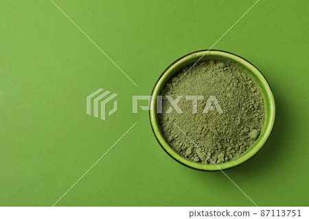 Bowl of matcha powder on green background 87113751