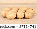 Many walnuts lie in a heap on a wooden background 87114741