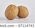 Two large walnuts lie side by side on a white background. 87114743