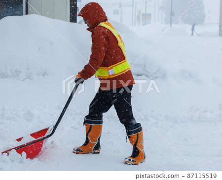 A man who is working on snow gathering in winter Snow scoop 87115519