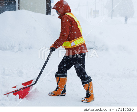 A man who is working on snow gathering in winter Snow scoop 87115520