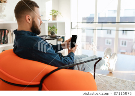 Man Using Phone With Empty Screen Sitting In Chair Indoors Man Using Phone With Empty Screen Sitting In Chair Indoors 87115975