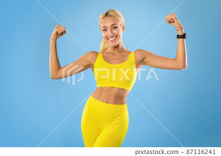 Happy sporty woman showing strong biceps muscles at studio Happy sporty woman showing strong biceps muscles at studio 87116241