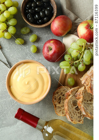 Concept of delicious food with fondue on gray textured table Concept of delicious food with fondue on gray textured table 87116399