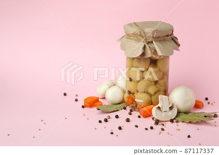 Jar with marinated mushrooms on pink background 87117337