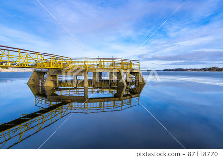 Yellow spilway with reflection on the water Yellow spilway with reflection on the water 87118770