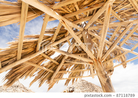 Old wooden umbrella with holes on a sunny day Old wooden umbrella with holes on a sunny day 87118789