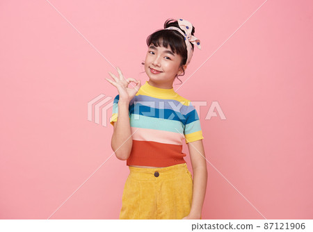 Asian cheerful happy girl showing OK gesture smiling isolated on pink background. 87121906