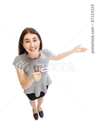 High angle view of emotional young girl, female journalist holding reporter microphone isolated on white studio background. Concept of social media, press, news, information 87123229