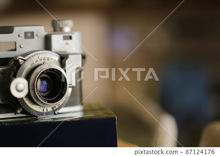 Vintage old photography film camera with lens on a book. Close up shot Vintage old photography film camera with lens on a book. Close up shot 87124176