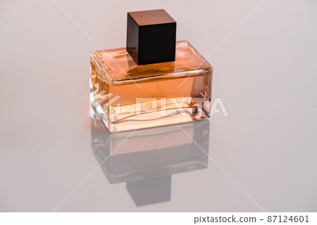 Glass perfume bottle with rosemary sprig on wooden podium 87124601