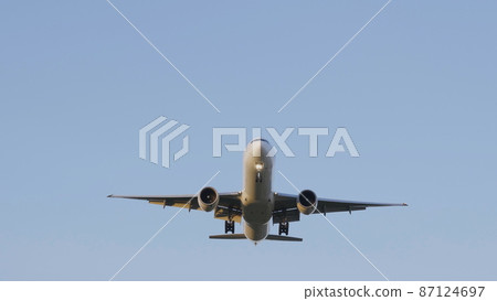 Commercial passenger airplane flying overhead on sunny day 87124697