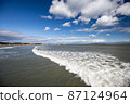 Waves crashing against the blue sky 87124964