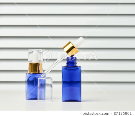 blue glass bottle with a pipette on a white background. Template for cosmetic liquid products, advertising and promotion 87125901