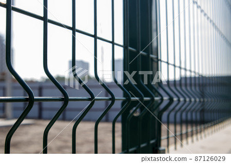 Steel lattice green fence with wire. Fencing. Grid industrial wire fence panels, pvc metal. Installation of sectional fencing. Welded mesh fence. Installation of a grid for fencing the territory. 87126029