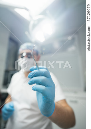 Dentist holding a dental mirror  87126079
