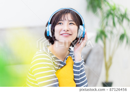 Young woman listening to music on headphones Young woman listening to music on headphones 87126456