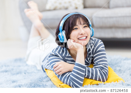 年輕女子躺下,用耳機聽音樂 年輕女子躺下,用耳機聽音樂 87126458