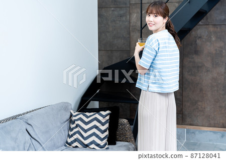 A woman relaxing with a cup of tea in the living room A woman relaxing with a cup of tea in the living room 87128041