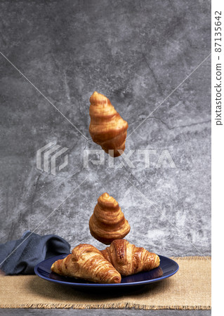 Group of croissants falling on a blue plate. Sweets and desserts 87135642