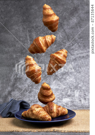 Group of croissants falling on a blue plate. Sweets and desserts Group of croissants falling on a blue plate. Sweets and desserts 87135644