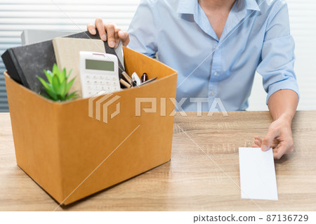 Resignation Concept The male officer sitting, putting his box of his belongs on the desk and handing the white letter to someone 87136729