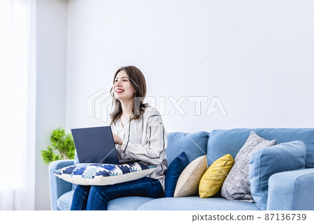 一位微笑的年輕女子在房間裡操作筆記本電腦 一位微笑的年輕女子在房間裡操作筆記本電腦 87136739