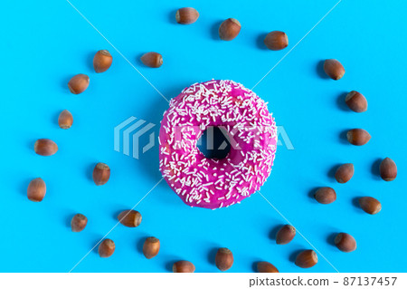 Donut with hazelnuts on blue background, close up Donut with hazelnuts on blue background, close up 87137457
