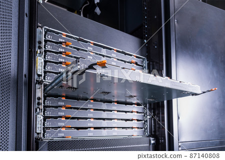 Slot for the hard drives is sticking out in the server room. Computer equipment of the Internet provider is in the data center. Hosting site with a large database. 87140808