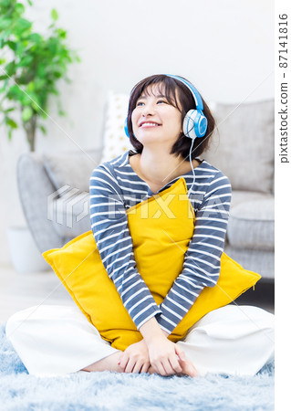 Young woman listening to music on headphones Young woman listening to music on headphones 87141816