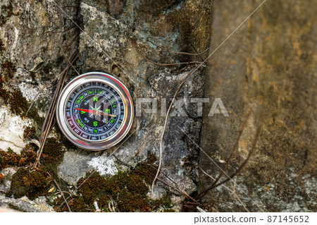 The compass is placed on the rock like a mountain, giving the mood of adventure travel on vacation. The compass is placed on the rock like a mountain, giving the mood of adventure travel on vacation. 87145652