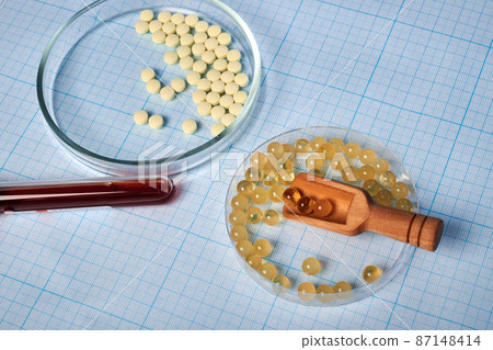 Petri Dishes with Vitamins and Wooden Scoop - Photo on Graph Paper Petri Dishes with Vitamins and Wooden Scoop - Photo on Graph Paper 87148414