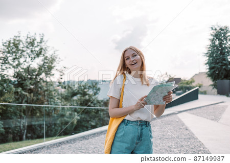 Young blonde female tourist traveler looking for the right direction on a trip map a city street, traveling in Europe. Tourism, destination concept Young blonde female tourist traveler looking for the right direction on a trip map a city street, traveling in Europe. Tourism, destination concept 87149987
