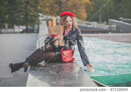 Pretty casual blond woman in stylish black jacket in the city Pretty casual blond woman in stylish black jacket in the city 87150004
