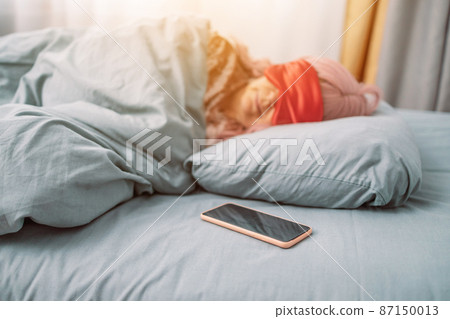 Sweet Dreams. Beautiful caucasian woman in eye mask sleeping in bed early in morning. People, relax and comfort 87150013