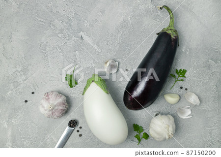 White and blue fresh raw eggplant vegetable and garlic on grey background, top view. Healthy vegetarian diet food White and blue fresh raw eggplant vegetable and garlic on grey background, top view. Healthy vegetarian diet food 87150200
