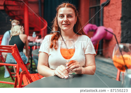 Happy woman drinking classic italian aperitif aperol spritz cocktail. Traditional summer fresh drink Happy woman drinking classic italian aperitif aperol spritz cocktail. Traditional summer fresh drink 87150223