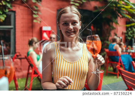Happy woman with glass of icy aperol spritz cocktail at the restaurant. Happy woman with glass of icy aperol spritz cocktail at the restaurant. 87150224