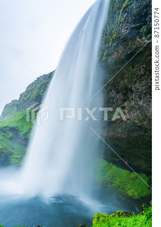 Natural landscape of beautiful Seljalandsfoss Waterfalls in summer cloudy day. Natural landscape of beautiful Seljalandsfoss Waterfalls in summer cloudy day. 87150774