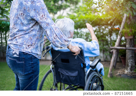Caregiver help and care Asian senior or elderly old lady woman patient sitting on wheelchair at park in nursing hospital ward, healthy strong medical concept. 87151665