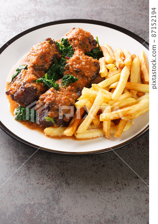 Rabo De Toro delicious dish in Spain is oxtail stew served with french fry closeup in the plate. Vertical Rabo De Toro delicious dish in Spain is oxtail stew served with french fry closeup in the plate. Vertical 87152194