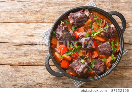 Traditional spanish dish slow cooked oxtail in red wine sauce with rabo de toro closeup on a pot on the table. Horizontal top view Traditional spanish dish slow cooked oxtail in red wine sauce with rabo de toro closeup on a pot on the table. Horizontal top view 87152196