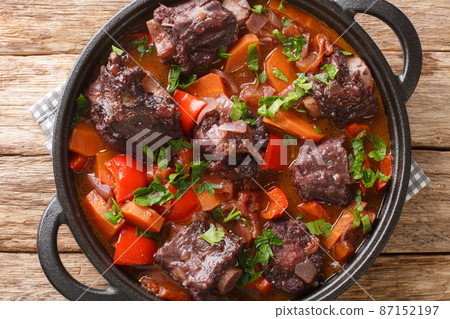 Beef tail oxtail stew cooked in traditional spanish food rabo de toro closeup on a pot on the table. Horizontal top view Beef tail oxtail stew cooked in traditional spanish food rabo de toro closeup on a pot on the table. Horizontal top view 87152197