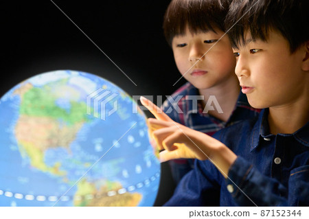 Two children staring at a glowing globe 87152344
