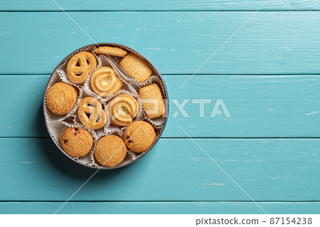 Sweet danish butter biscuits in an open tin on a turquoise wooden tabletop. Sweet danish butter biscuits in an open tin on a turquoise wooden tabletop. 87154238