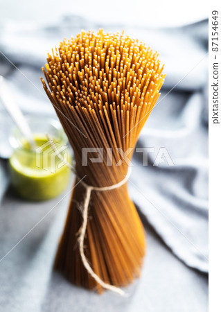 Uncooked whole grain spaghetti. Raw pasta on kitchen table. Uncooked whole grain spaghetti. Raw pasta on kitchen table. 87154649