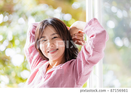 一個清爽的女人站在窗邊沐浴晨光 87156981